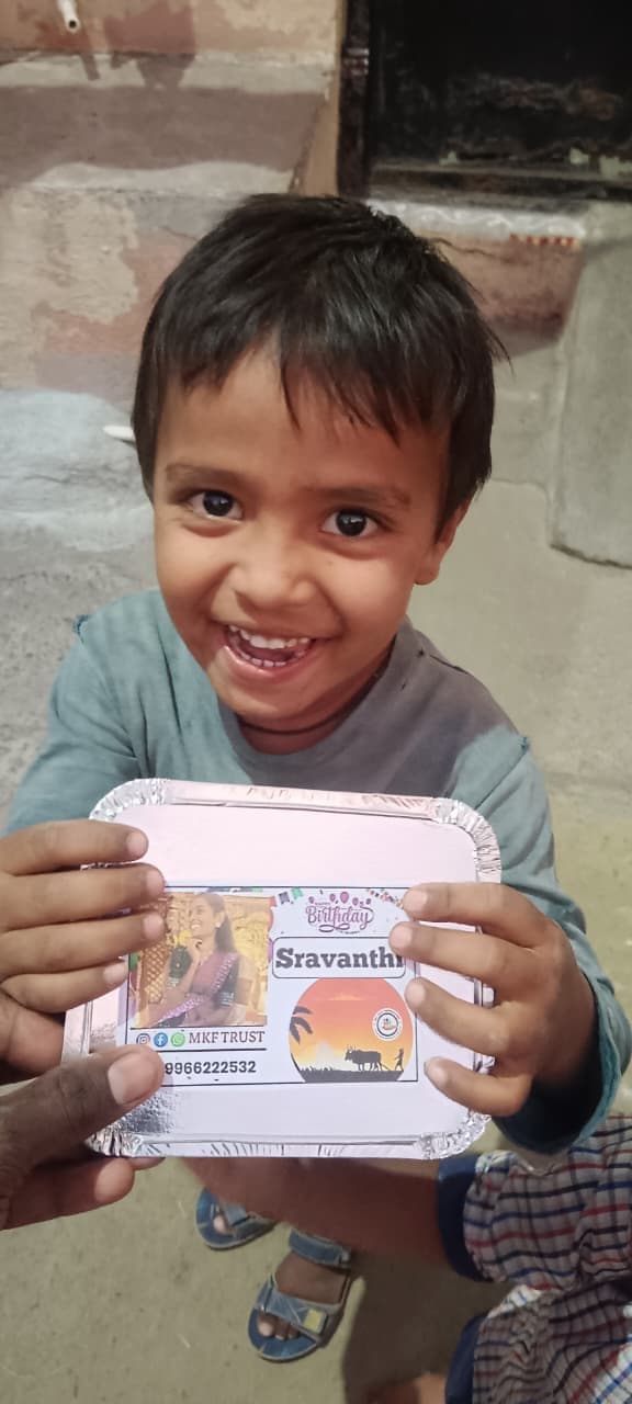 Child holding an Annadanam meal box with the donor's name, served by MKF Trust